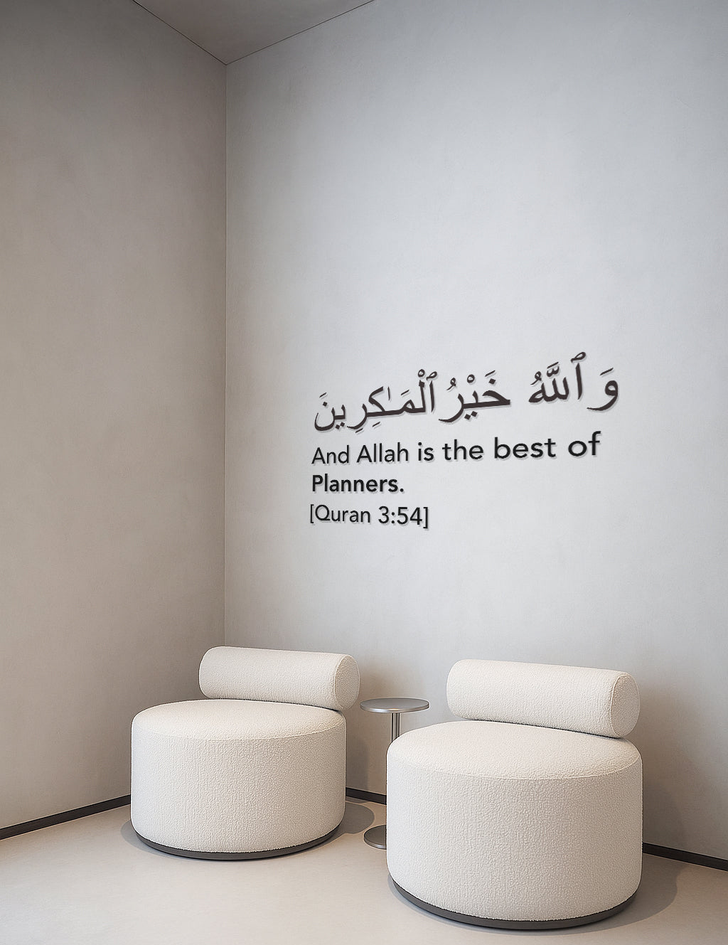 Minimalist Islamic wall art in a bright room with two white boucle chairs and a small round table. The wall displays a Quranic verse in Arabic and English: “And Allah is the best of planners” [Quran 3:54] – ideal for modern Muslim decor.